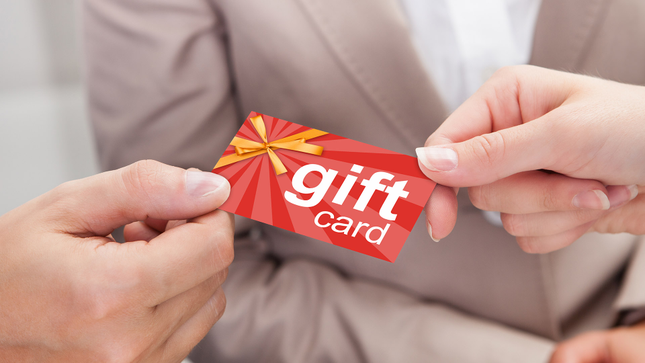 Un'immagine mostra qualcuno che regala a una persona una carta regalo. 